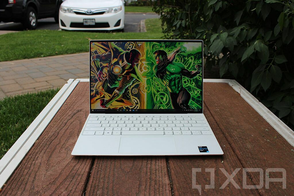 Dell XPS 13 על ספסל עץ עם מכונית ברקע