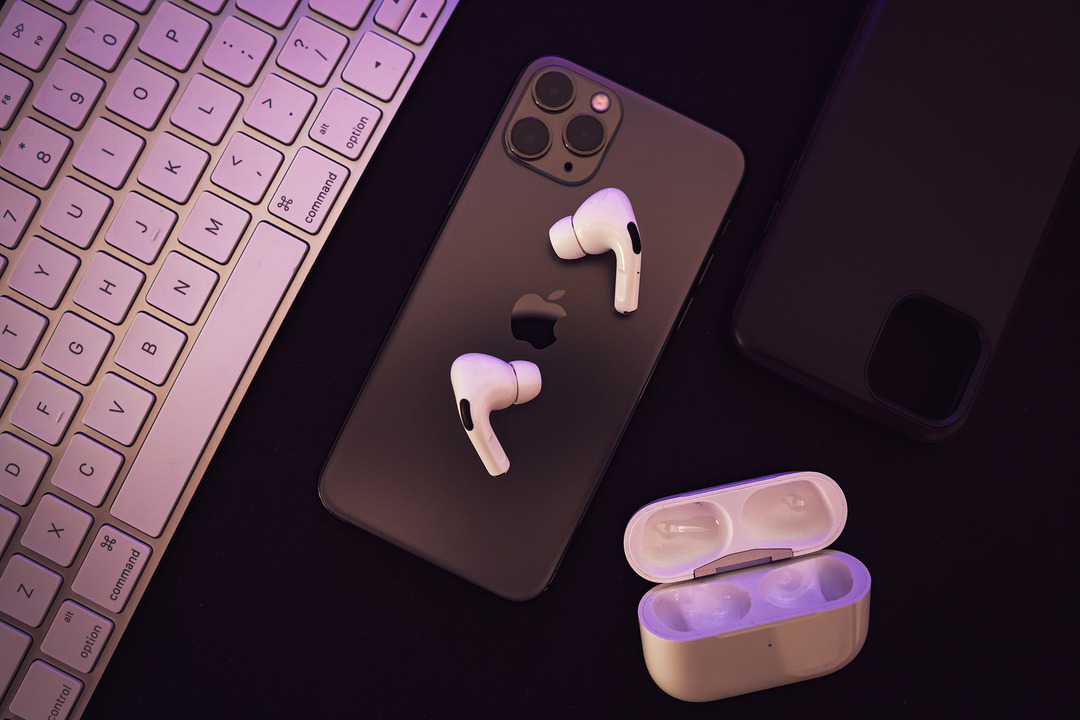 Az AirPods Pro iPhone-on nyugszik nyitott töltőtokkal a közelben.