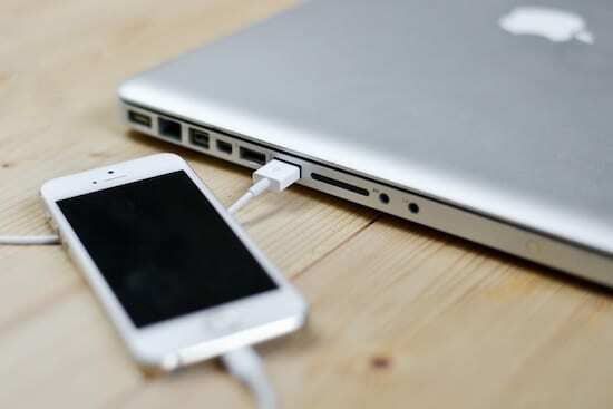 iPhone terhubung ke MacBook dengan kabel petir.