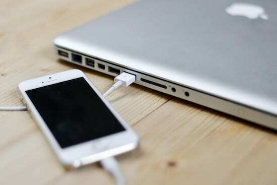 iPhone დაკავშირებულია MacBook-თან lightning კაბელით.