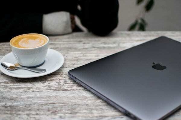 Zavřený MacBook vedle šálku kávy