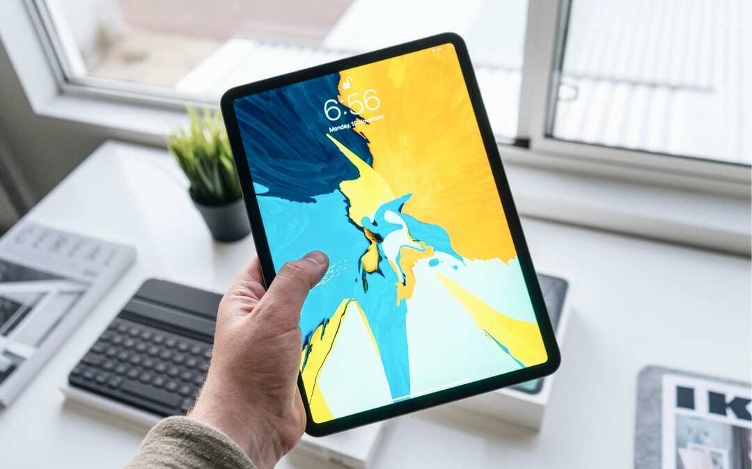 شخص يحمل جهاز iPad فوق مكتب.