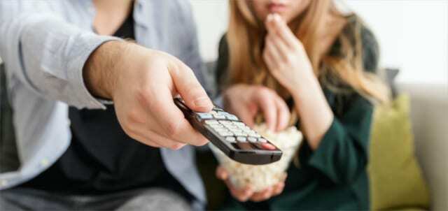 Man en vrouw die een afstandsbediening van een televisie gebruiken