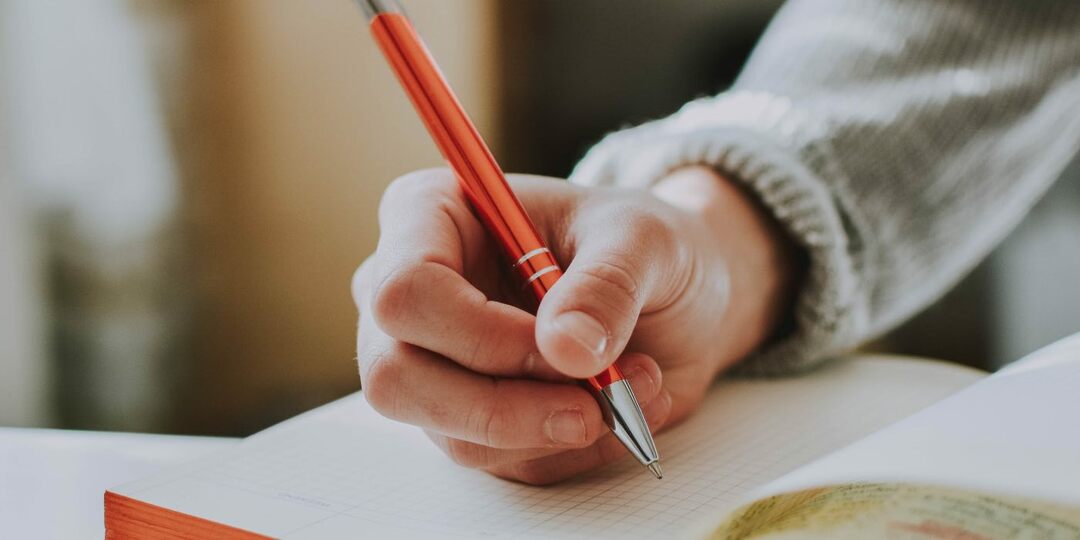 foto van een persoon die in een boek schrijft