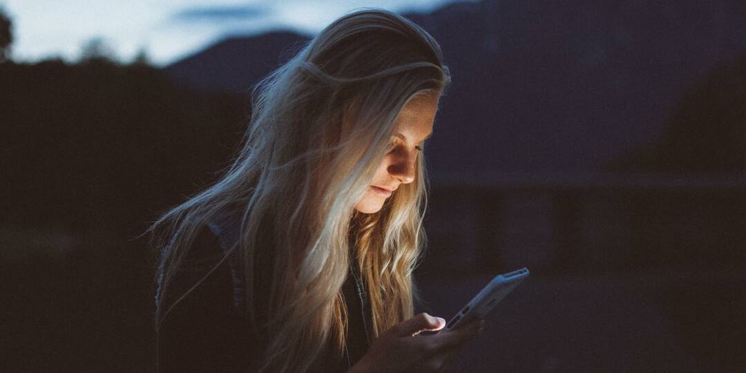 Fénykép egy személyről, aki az iPhone-ját bámulja