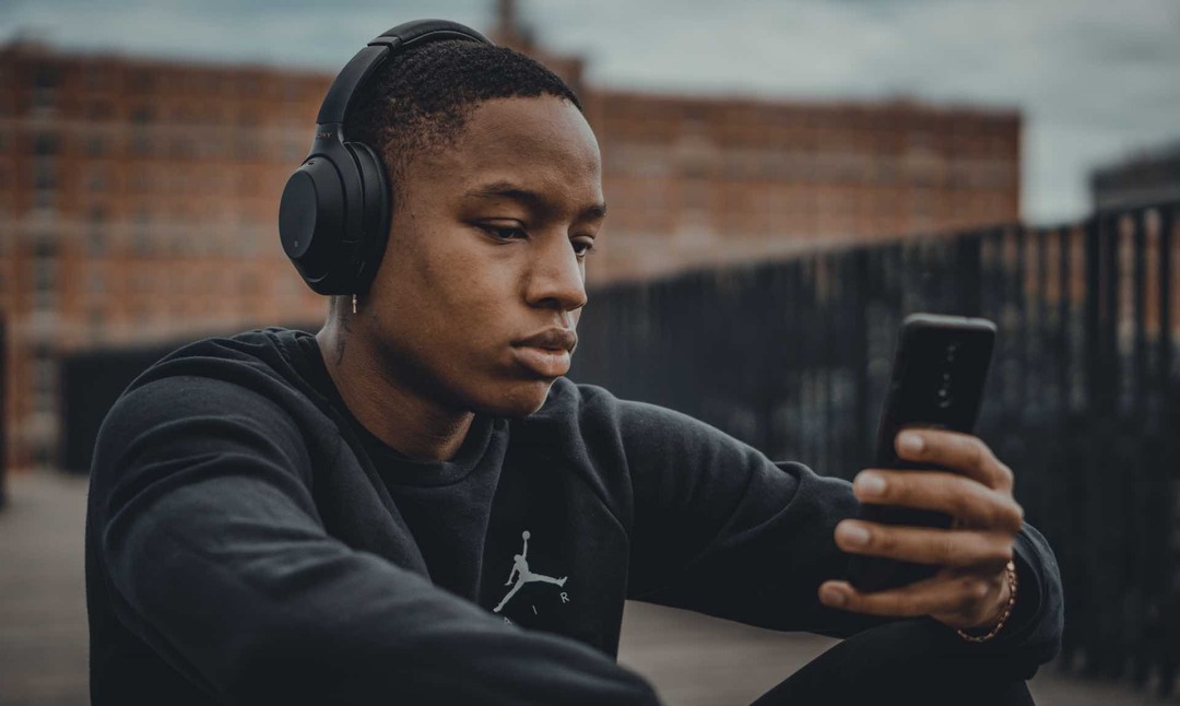 foto seseorang mendengarkan musik dan mencari telepon mereka