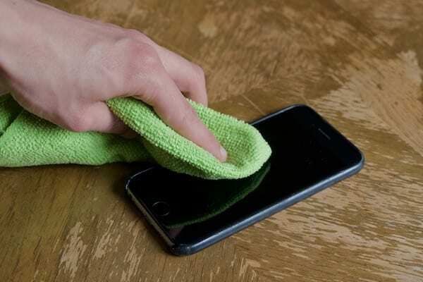 Fotografia iPhonu, ktorý sa čistí zelenou handričkou z mikrovlákna