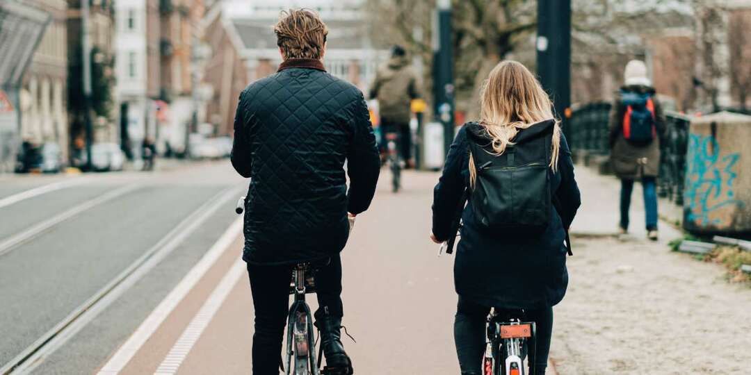 фото двух людей, катающихся на велосипеде по городу рядом друг с другом