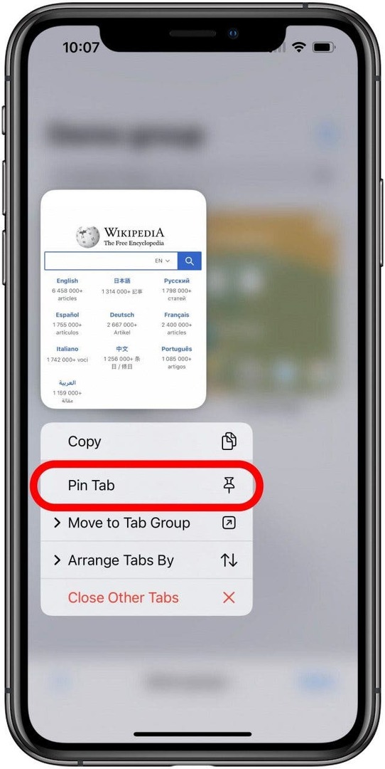 Safari-app med faneskærmen for en fanegruppe sløret i baggrunden og en enkelt fane synlig med den lange trykmenu åben under den. Indstillingen Pin Tab er markeret i menuen.