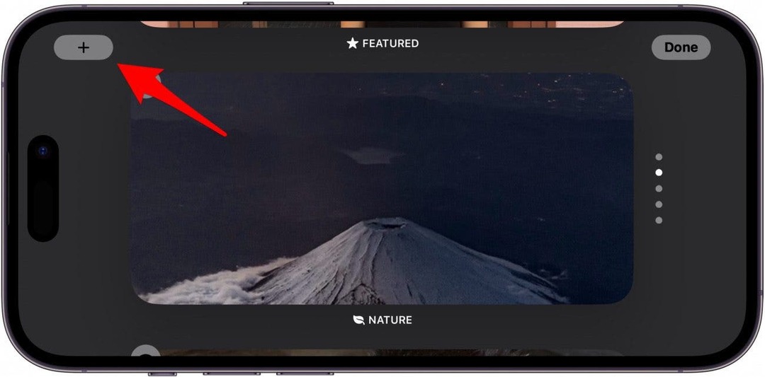 מסך תמונות המתנה של אייפון עם חץ אדום המצביע על סמל הפלוס