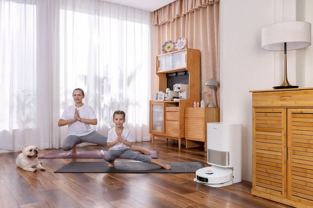 Mutter und Tochter machen Yoga mit dem DreameBot L10S Ultra in seiner Dockingstation 