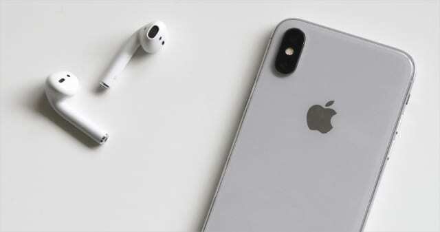 सफेद सतह पर iPhone के बगल में AirPods