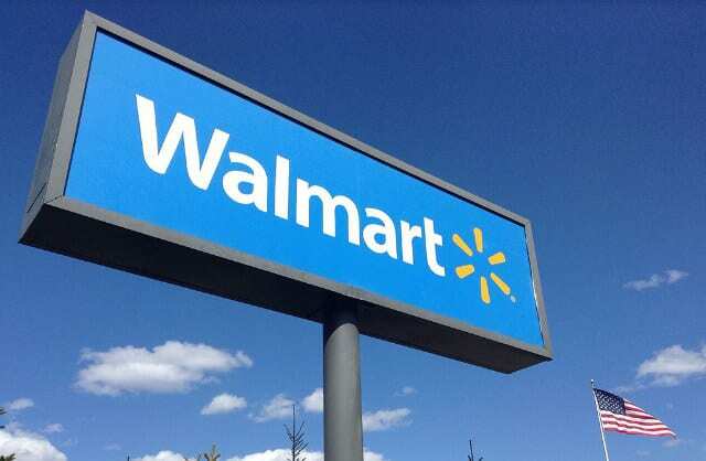 Walmart-skylt bredvid en amerikansk flagga framför en blå himmel