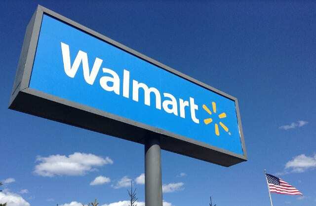 Panneau Walmart à côté d'un drapeau américain devant un ciel bleu