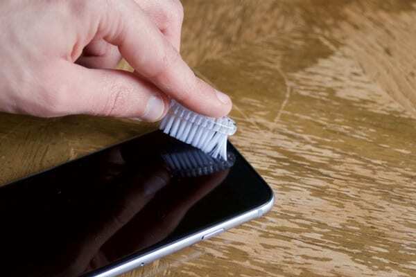 iPhone mikrofonunu temizlemek için yumuşak bir diş fırçası kullanma