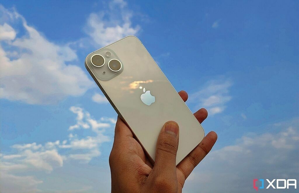 iPhone 14 na cor branca na mão contra o pano de fundo do céu azul