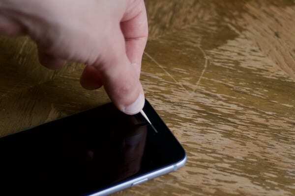 Fotografija čačkalice koja se koristi za čišćenje iPhone zvučnika.